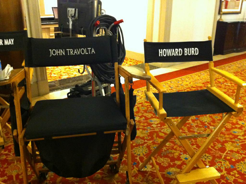 Production chairs on set labeled John Travolta and Howard Burd